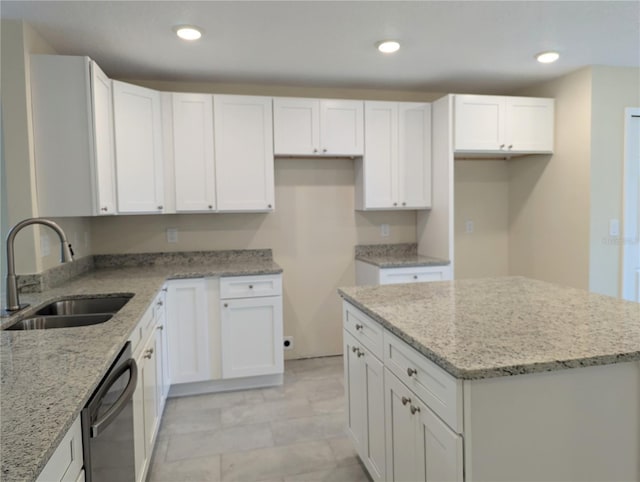 kitchen featuring white cabinets, stainless steel dishwasher, light stone counters, and sink