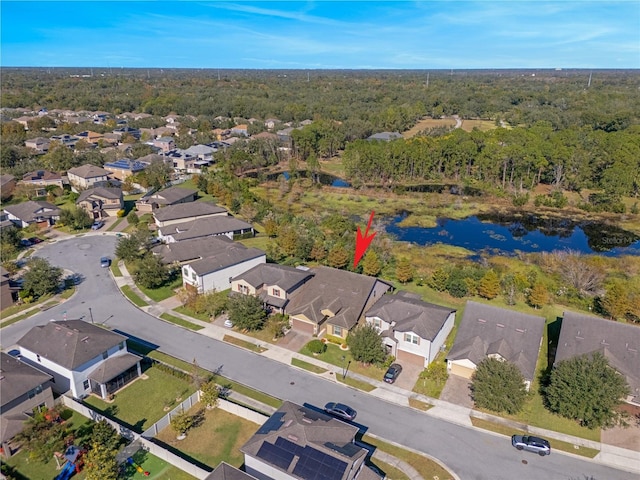 drone / aerial view featuring a residential view, a water view, and a view of trees