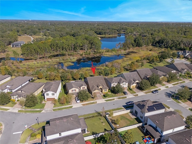 drone / aerial view featuring a water view, a residential view, and a wooded view