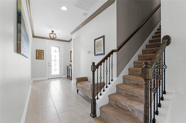 foyer entrance with crown molding, light tile patterned floors, visible vents, baseboards, and stairs