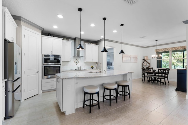 kitchen featuring visible vents, appliances with stainless steel finishes, a sink, wall chimney range hood, and backsplash