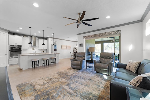 living area featuring recessed lighting, light wood-style flooring, ornamental molding, ceiling fan, and baseboards