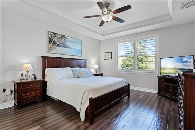 bedroom with dark wood-style floors, a raised ceiling, visible vents, and a textured ceiling