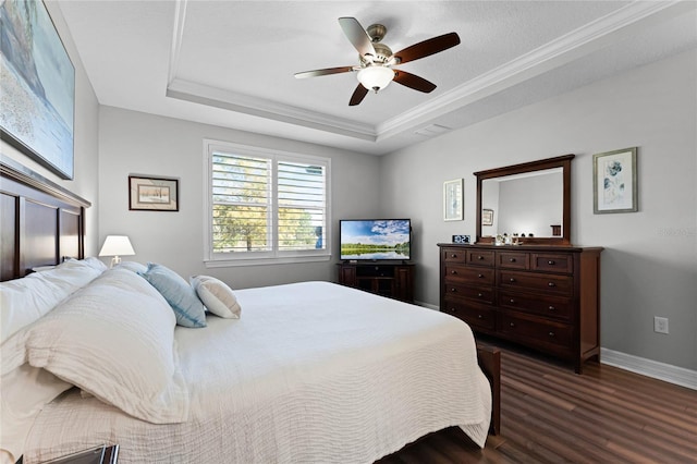 bedroom featuring a tray ceiling, dark wood-style flooring, crown molding, visible vents, and baseboards