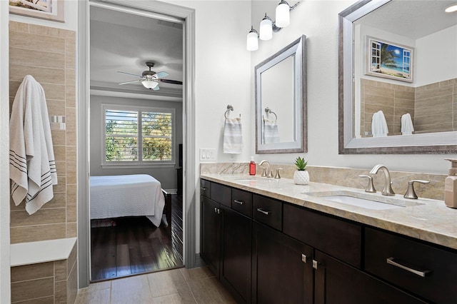 ensuite bathroom with double vanity, ensuite bath, a sink, and wood finished floors