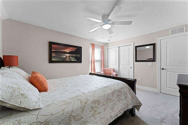 carpeted bedroom with a textured ceiling, visible vents, baseboards, a ceiling fan, and a closet