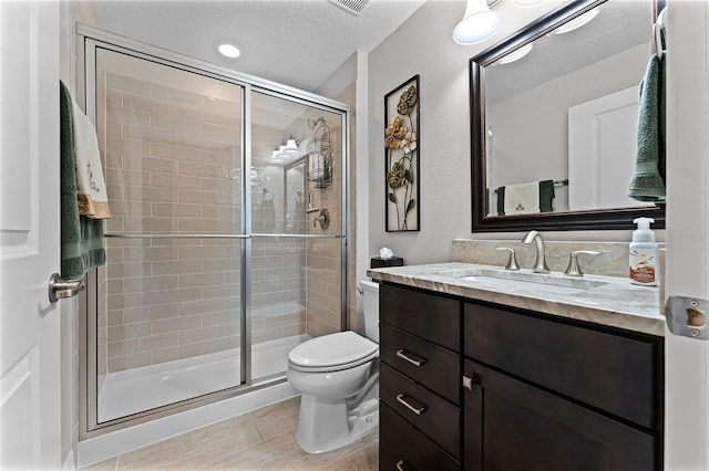 bathroom featuring a stall shower, a textured ceiling, toilet, and vanity