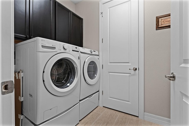 laundry area featuring washer and clothes dryer, cabinet space, and wood tiled floor