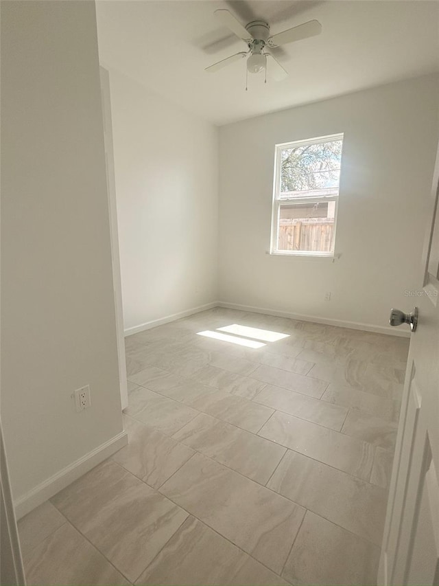 unfurnished room featuring a ceiling fan and baseboards