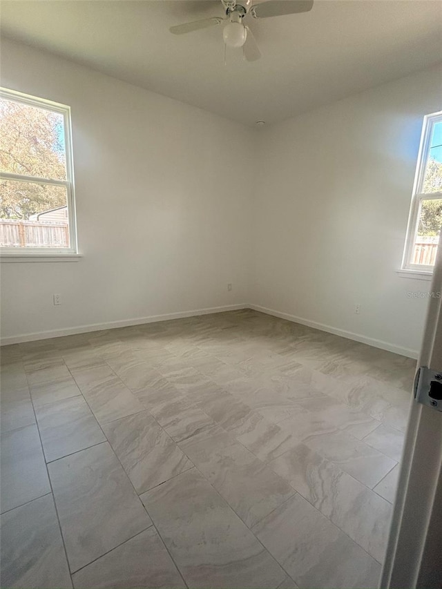 unfurnished room featuring a ceiling fan and baseboards