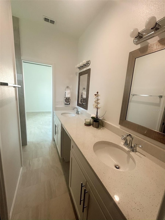 bathroom with double vanity, baseboards, visible vents, and a sink