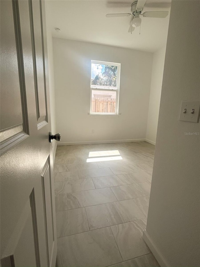 unfurnished room featuring ceiling fan and baseboards