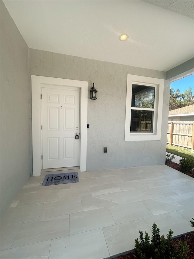 doorway to property featuring a patio area, fence, and stucco siding