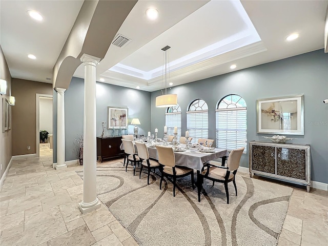 dining space with a tray ceiling and ornate columns