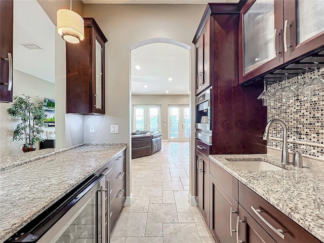 kitchen featuring decorative backsplash, light stone countertops, sink, and beverage cooler