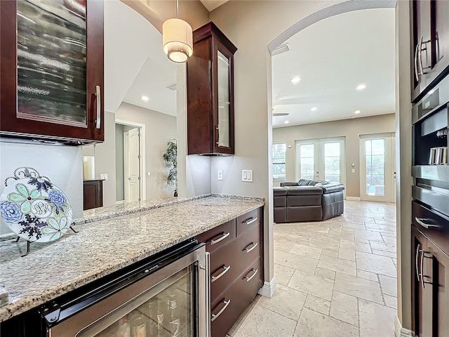 kitchen with wine cooler, light stone countertops, french doors, and stainless steel oven