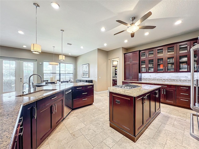 kitchen with light stone counters, ceiling fan, sink, decorative light fixtures, and a kitchen island