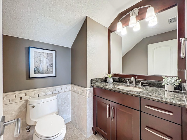 bathroom with lofted ceiling, vanity, tile walls, and toilet