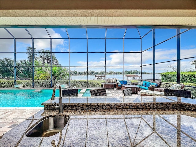 view of pool featuring outdoor lounge area, sink, a water view, and a patio