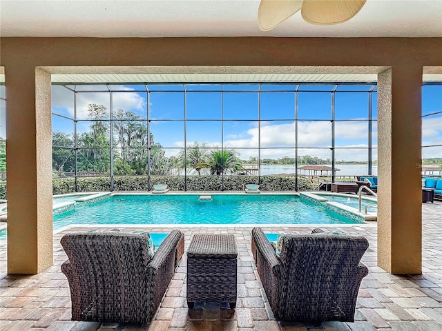 view of pool featuring glass enclosure, ceiling fan, and a patio area