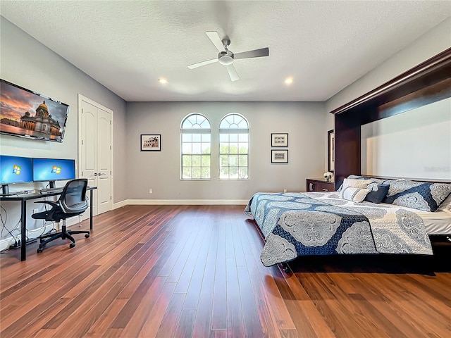 bedroom with ceiling fan, dark wood-type flooring, and a textured ceiling