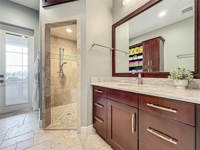 bathroom featuring a shower with door and vanity