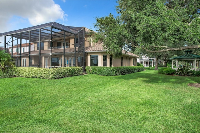 back of property with a yard and glass enclosure