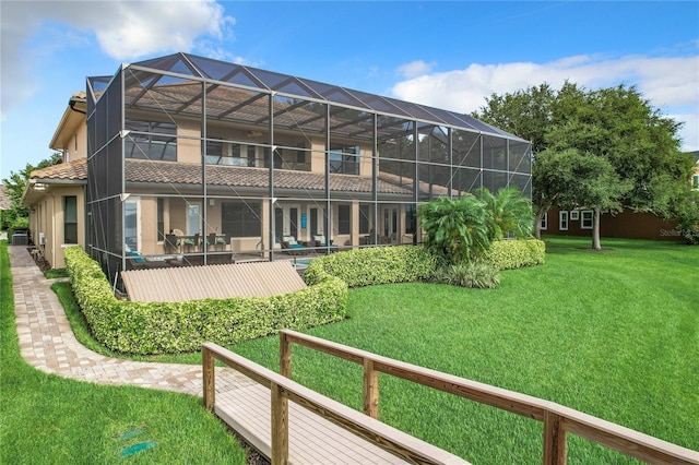 back of house featuring glass enclosure and a yard