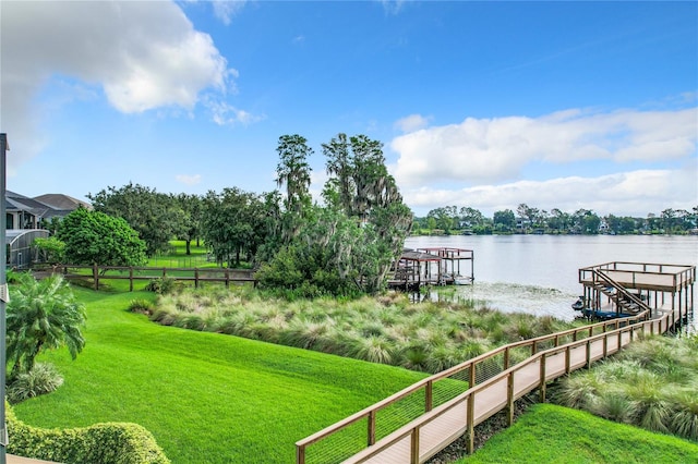 view of dock with a yard and a water view