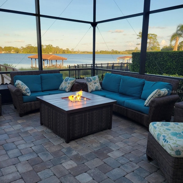 view of patio featuring outdoor lounge area, glass enclosure, and a water view