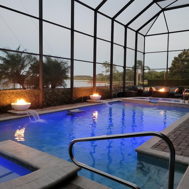 view of pool featuring pool water feature, a lanai, a fire pit, and a water view