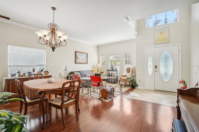 dining area with light hardwood / wood-style flooring, ornamental molding, and a notable chandelier