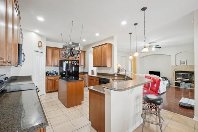 kitchen featuring a center island, sink, light hardwood / wood-style flooring, kitchen peninsula, and black appliances