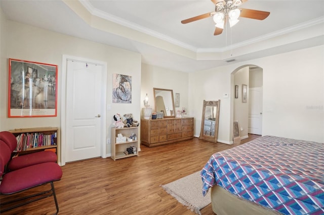 bedroom featuring hardwood / wood-style flooring, ceiling fan, crown molding, and a tray ceiling