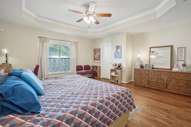 bedroom featuring hardwood / wood-style floors, a raised ceiling, ceiling fan, and ornamental molding