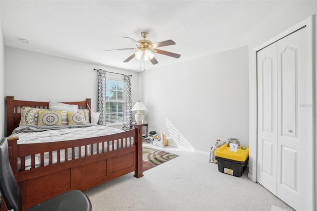 bedroom with ceiling fan, light carpet, and a closet