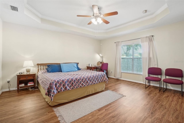 bedroom with a tray ceiling, ceiling fan, and hardwood / wood-style floors