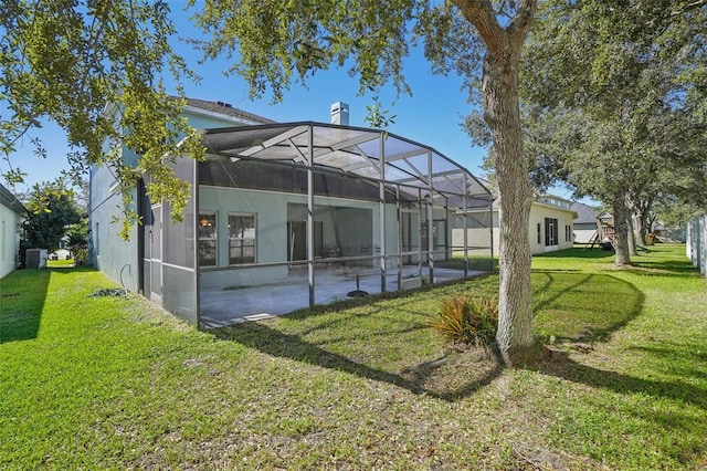 back of house with a yard, glass enclosure, and central AC unit