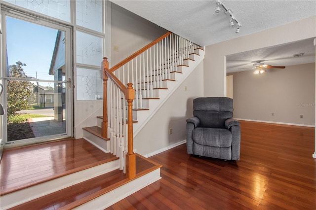 interior space with ceiling fan, hardwood / wood-style floors, rail lighting, and a textured ceiling