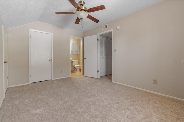 unfurnished bedroom with ceiling fan, light colored carpet, lofted ceiling, and connected bathroom