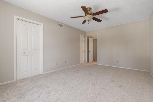 unfurnished bedroom featuring ceiling fan, light carpet, and multiple closets