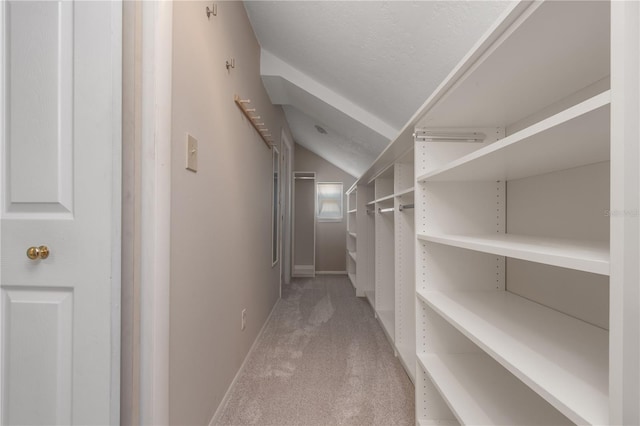 walk in closet featuring light colored carpet and lofted ceiling