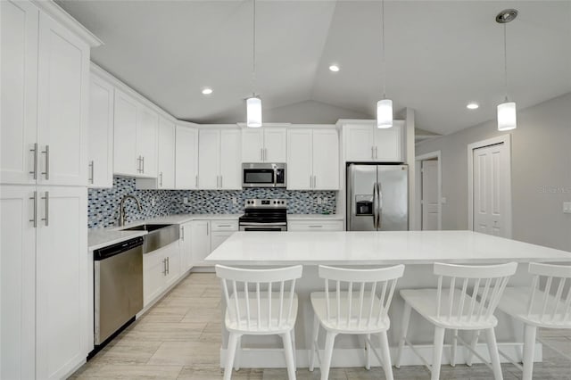 kitchen featuring hanging light fixtures, a center island, white cabinets, and stainless steel appliances