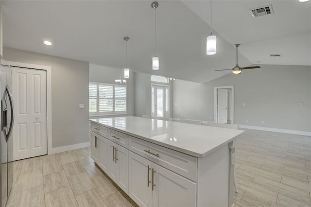 kitchen with ceiling fan with notable chandelier, vaulted ceiling, decorative light fixtures, a kitchen island, and white cabinetry