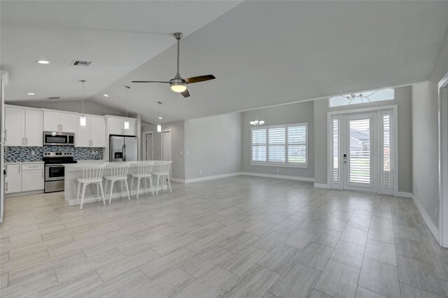 interior space featuring ceiling fan with notable chandelier and vaulted ceiling