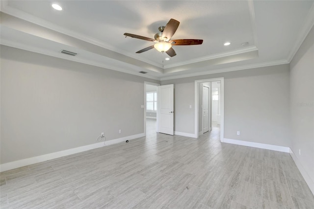 spare room featuring a tray ceiling, crown molding, ceiling fan, and light hardwood / wood-style floors