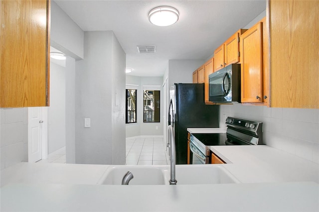 kitchen featuring stainless steel electric stove, light tile patterned floors, and tasteful backsplash