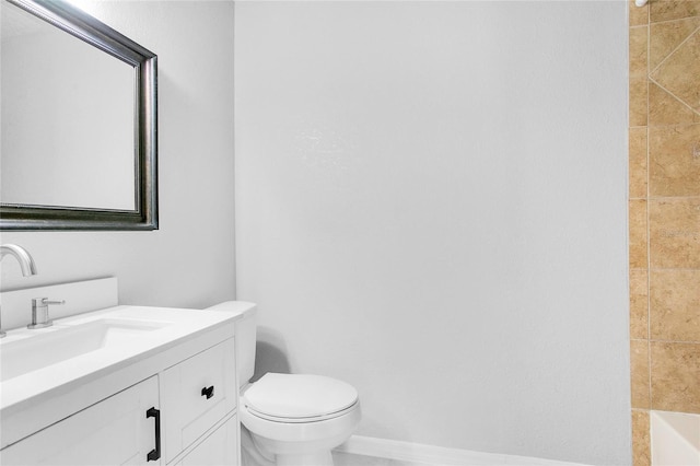 bathroom with a tile shower, vanity, and toilet