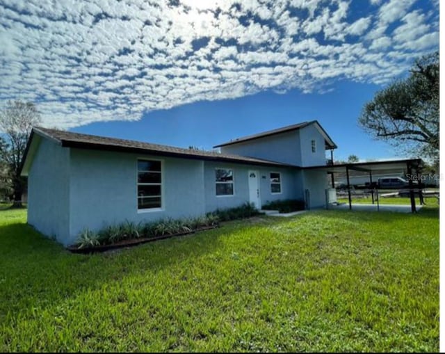 rear view of house featuring a yard and a carport