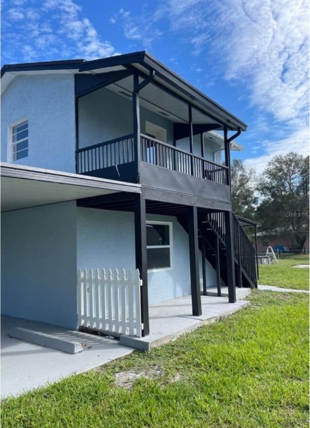 view of property exterior featuring a lawn, a balcony, and a patio